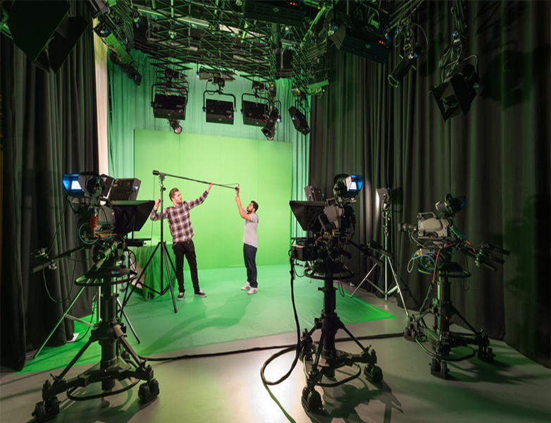 Two students setting up equipment in a green screen studio at MediaCity.