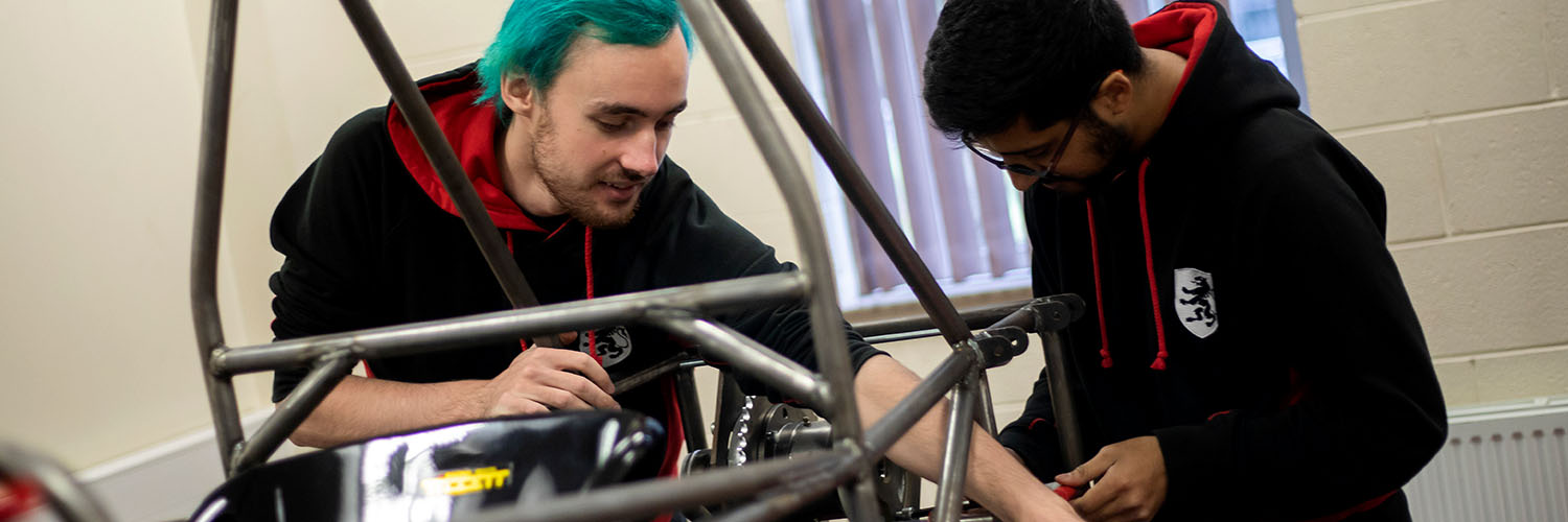 Two Mechanical Engineering students working on a racing car at the University of Salford