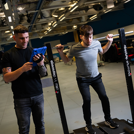 Students conducting strength tests with force plates with one student on the plates and the other reviewing the data on a tablet..