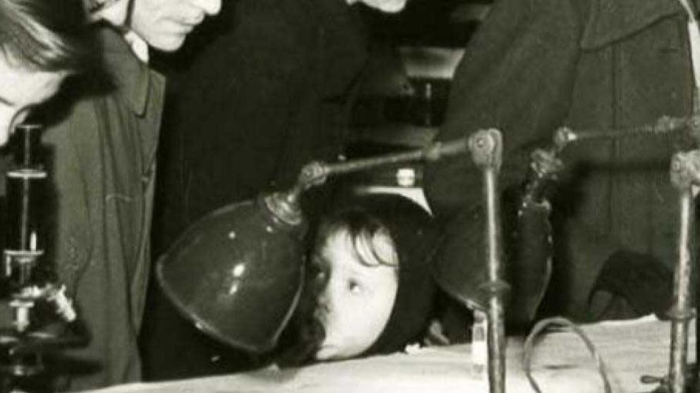Archive image: A black and white photo shows a boy using a microscope while a younger child looks on. 