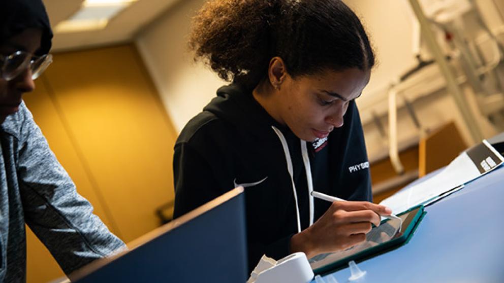 Two physiotherapy apprentices doing work on a tablet