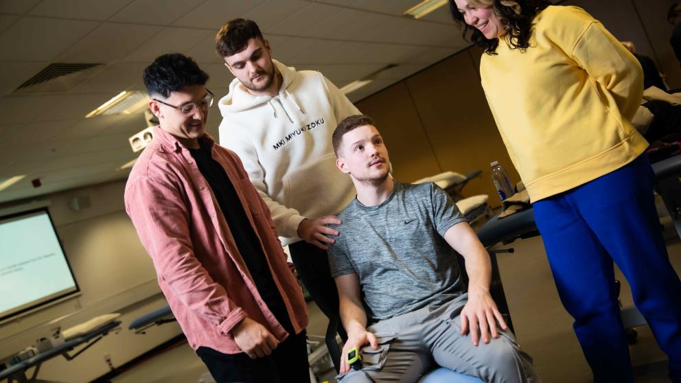 3 physiotherapy students standing up and one sitting down 