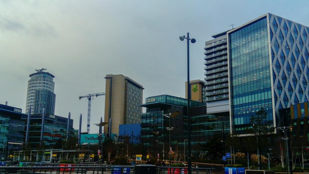 Skyline of MediaCity in Salford Quays with tall glass buildings, ITV and BBC buildings and crane in the background