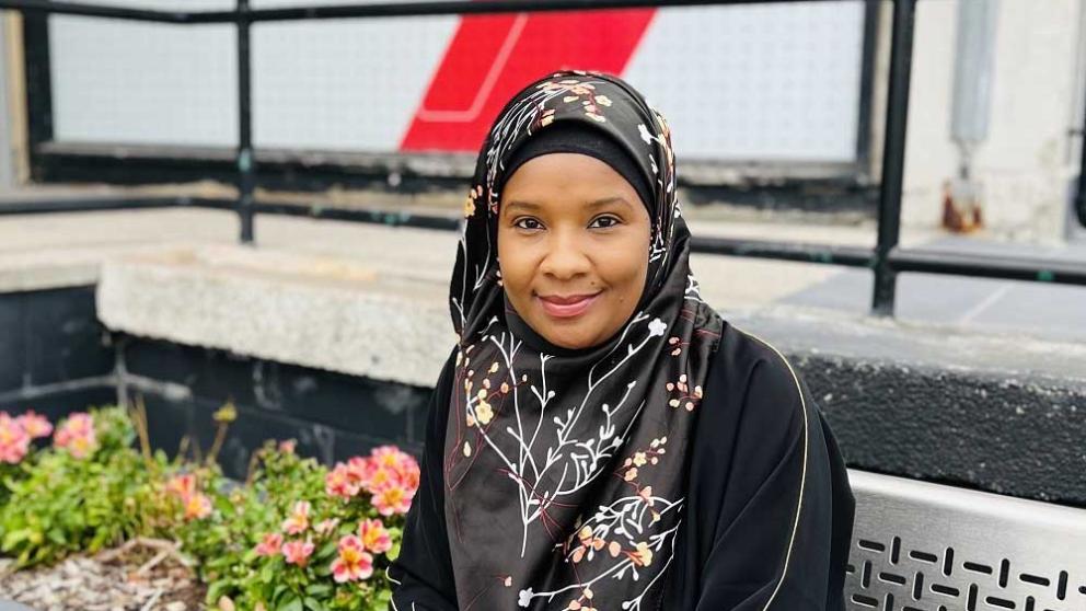 Aishatu Mohammed sat on bench in front of Maxwell Building, home of Salford Business School