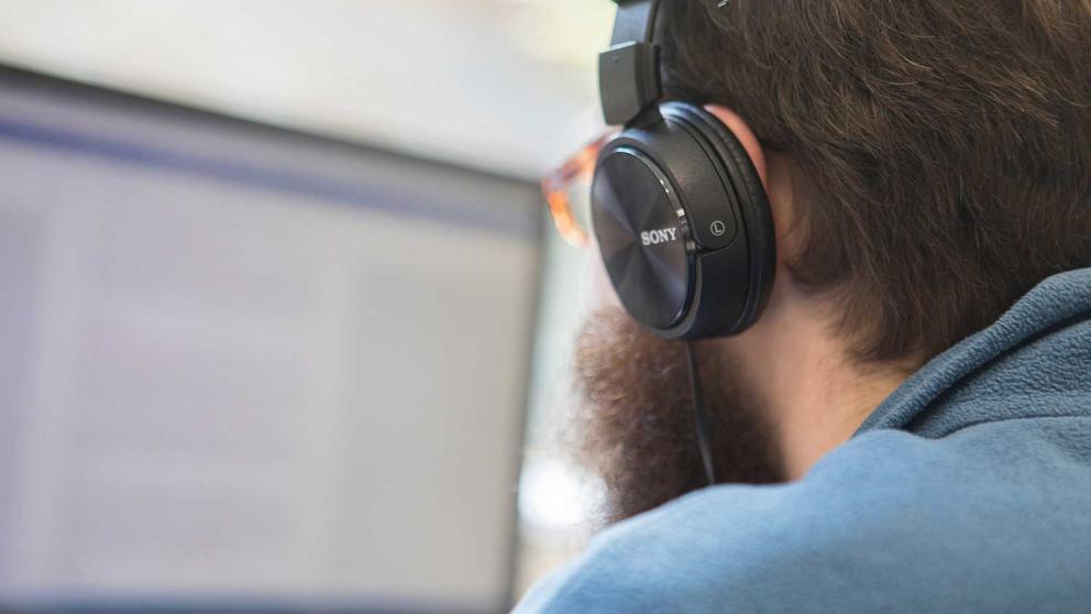 Student wearing headphones looking at a monitor