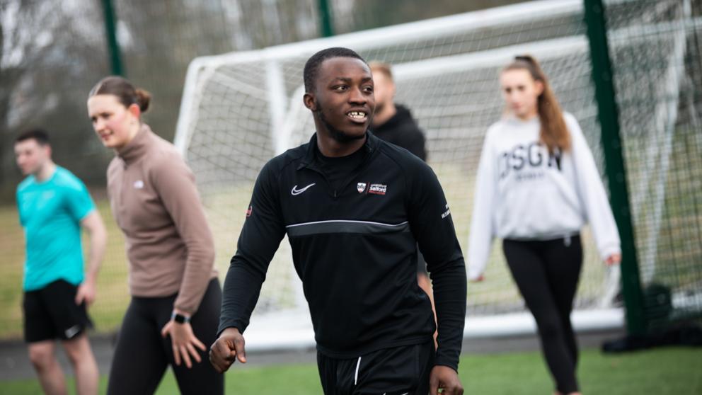 Male student looks off to the side whilst walking on the 3G Sports Pitch.