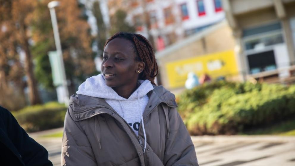 A female student wearing a coat sat talking to a friend in the middle of campus