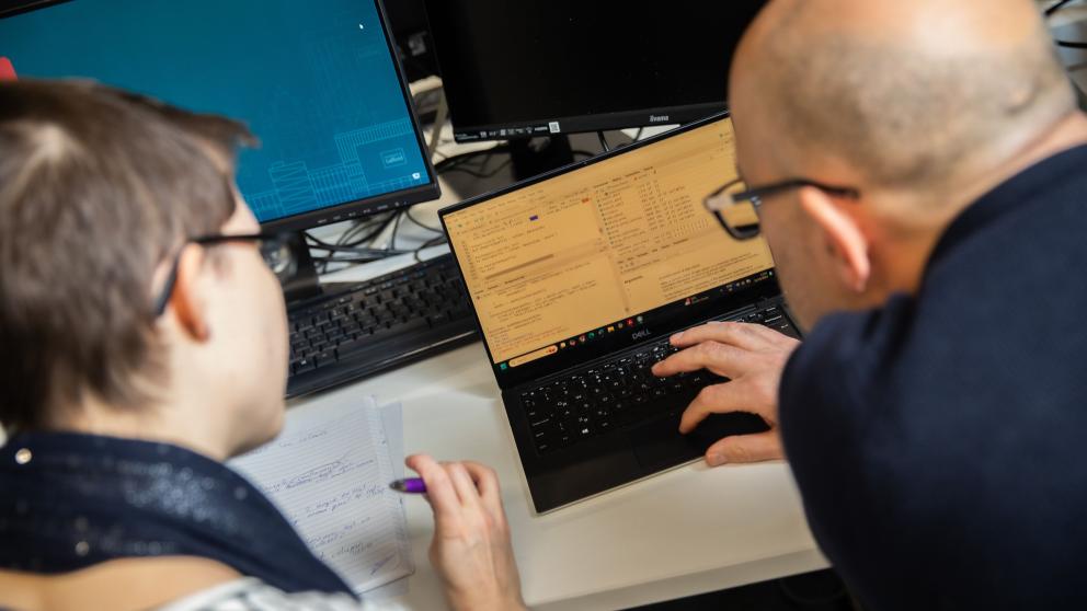 Student and academic working on a laptop together