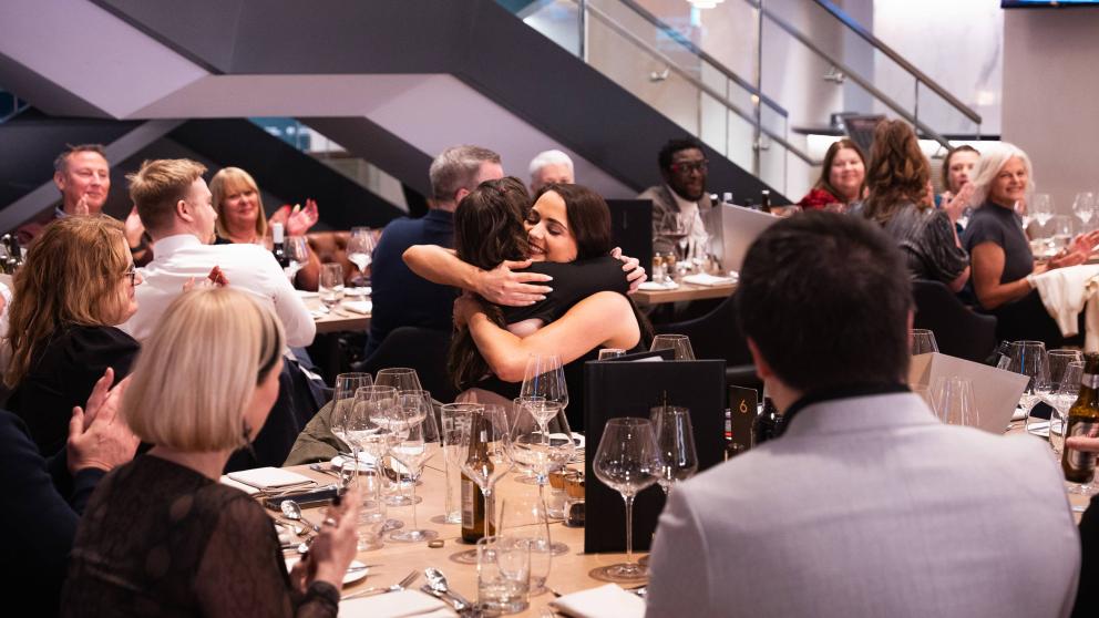 Staff members hugging to congratulate an award winner