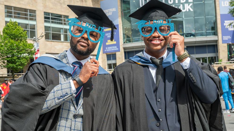 Two graduates with 'I did it' text branded glasses