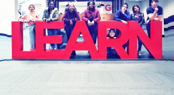 Eight students stood around the library learn sign