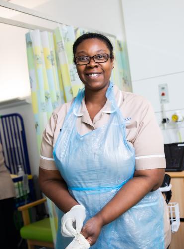 Female Nursing Associate apprentice putting on gloves on a simulation hospital ward