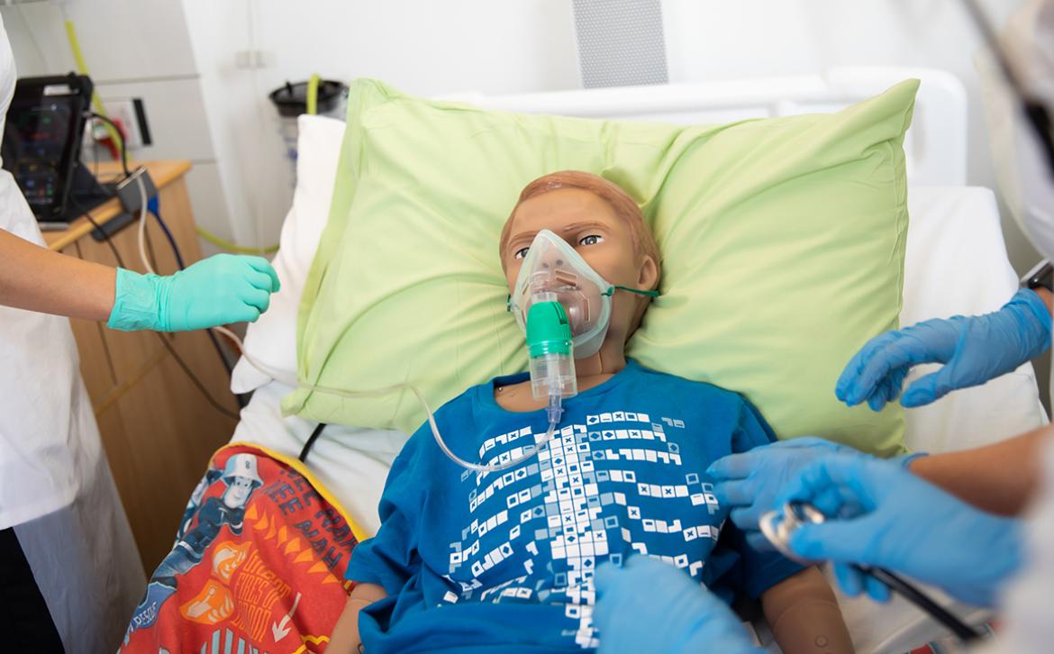 Human patient manakin in a hospital bed.